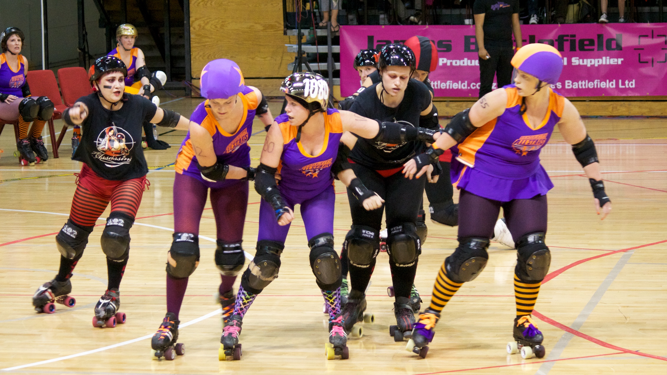 Roller derby players in full gear competing at high speed