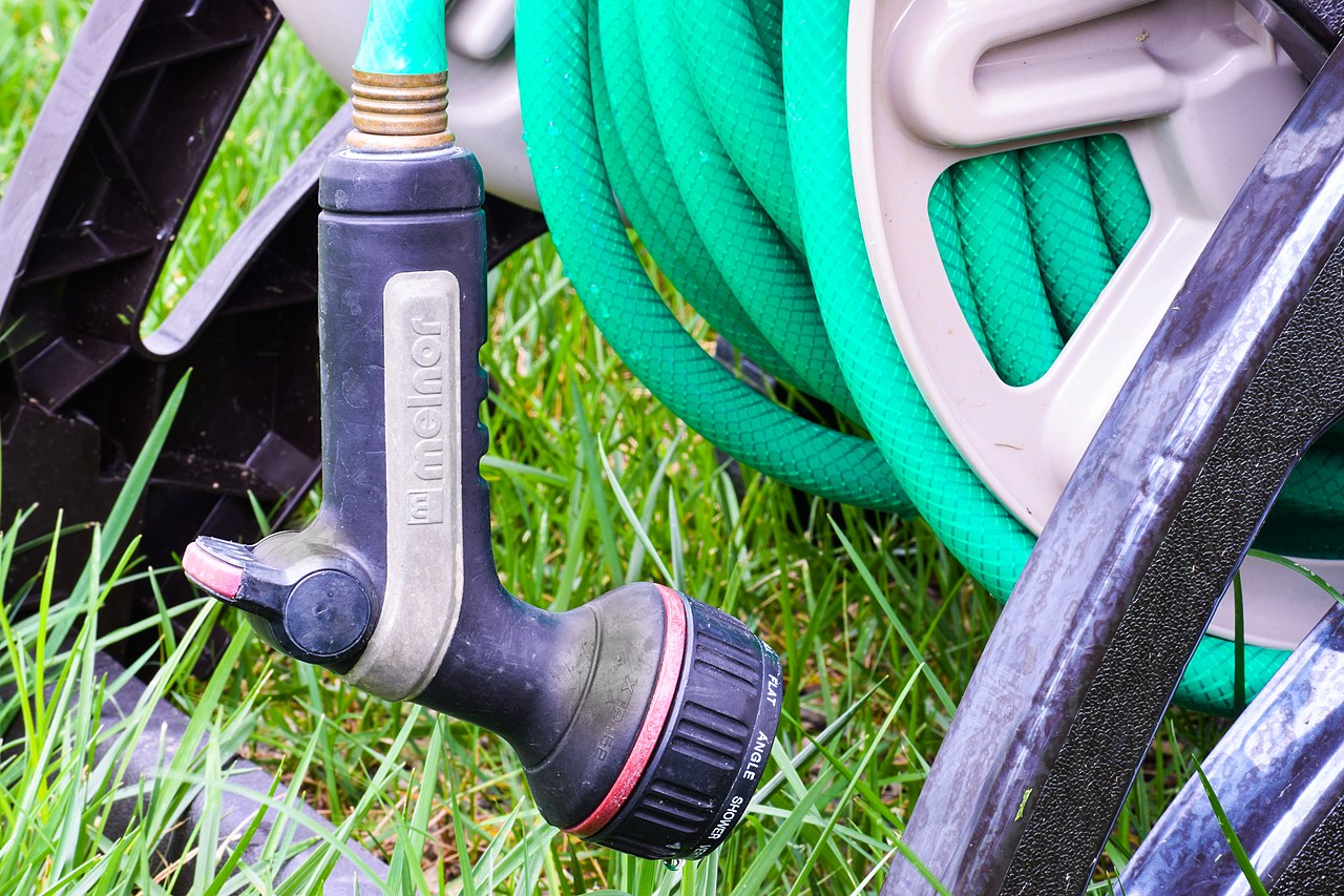 Garden hose reel with water nozzle in the backyard
