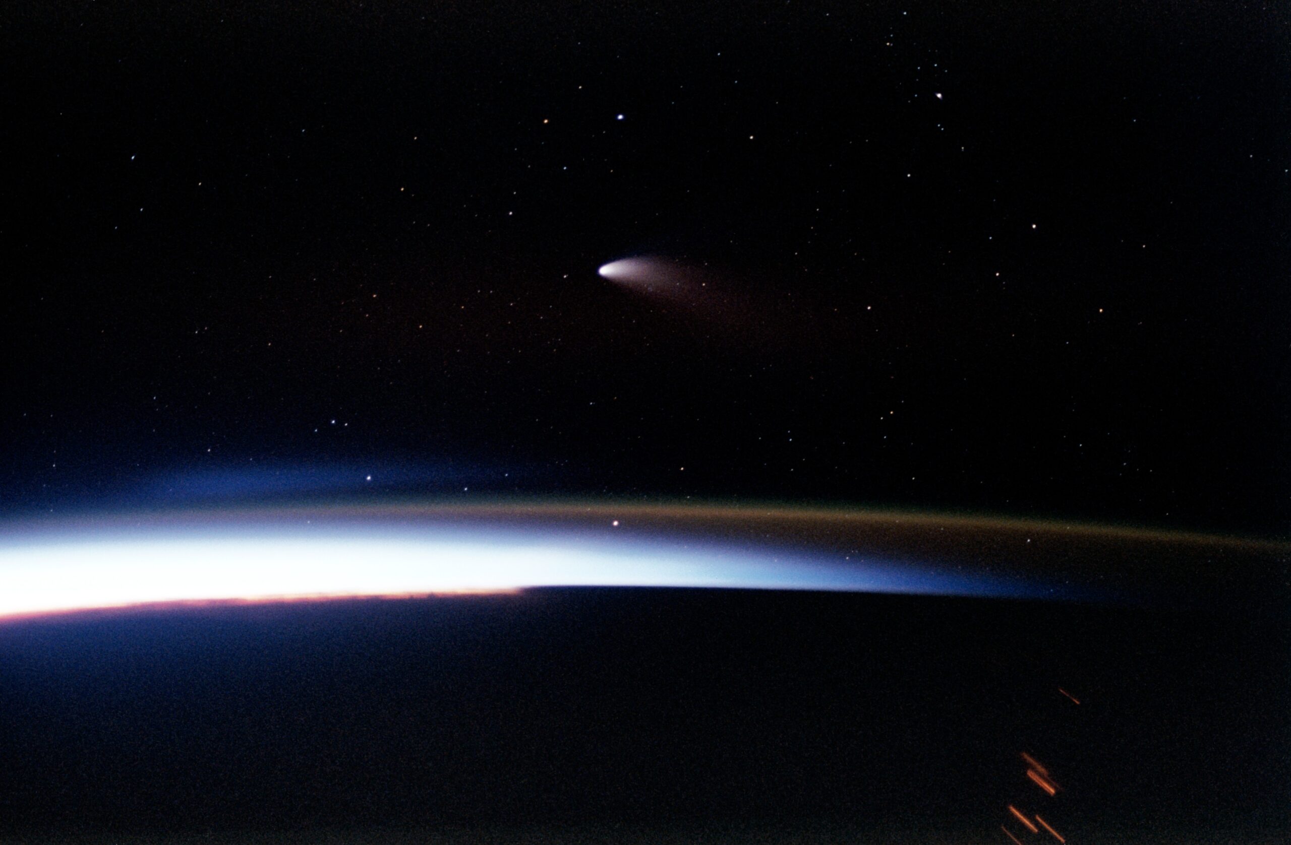 Hale-Bopp comet photographed from Space Shuttle Columbia during STS-83 mission April 1997 showing comet visible above Earth atmosphere