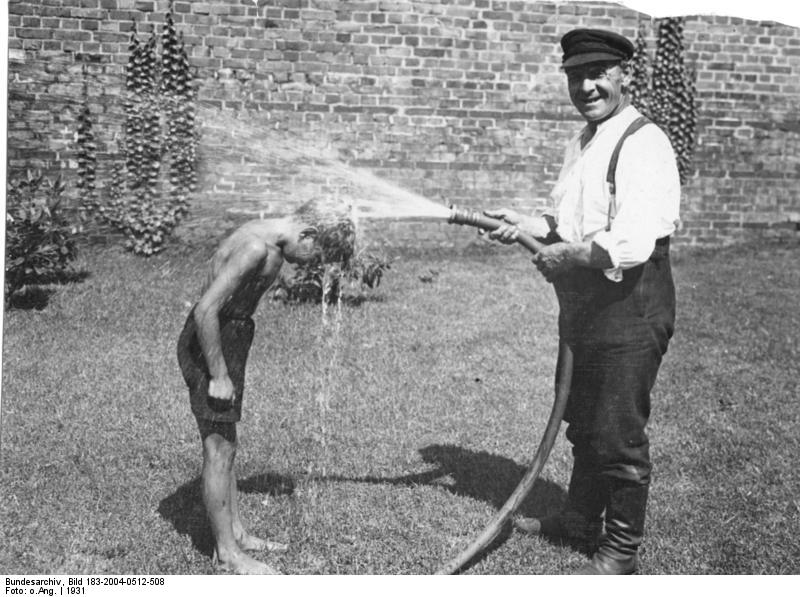 Vintage photo of children drinking water from a garden hose