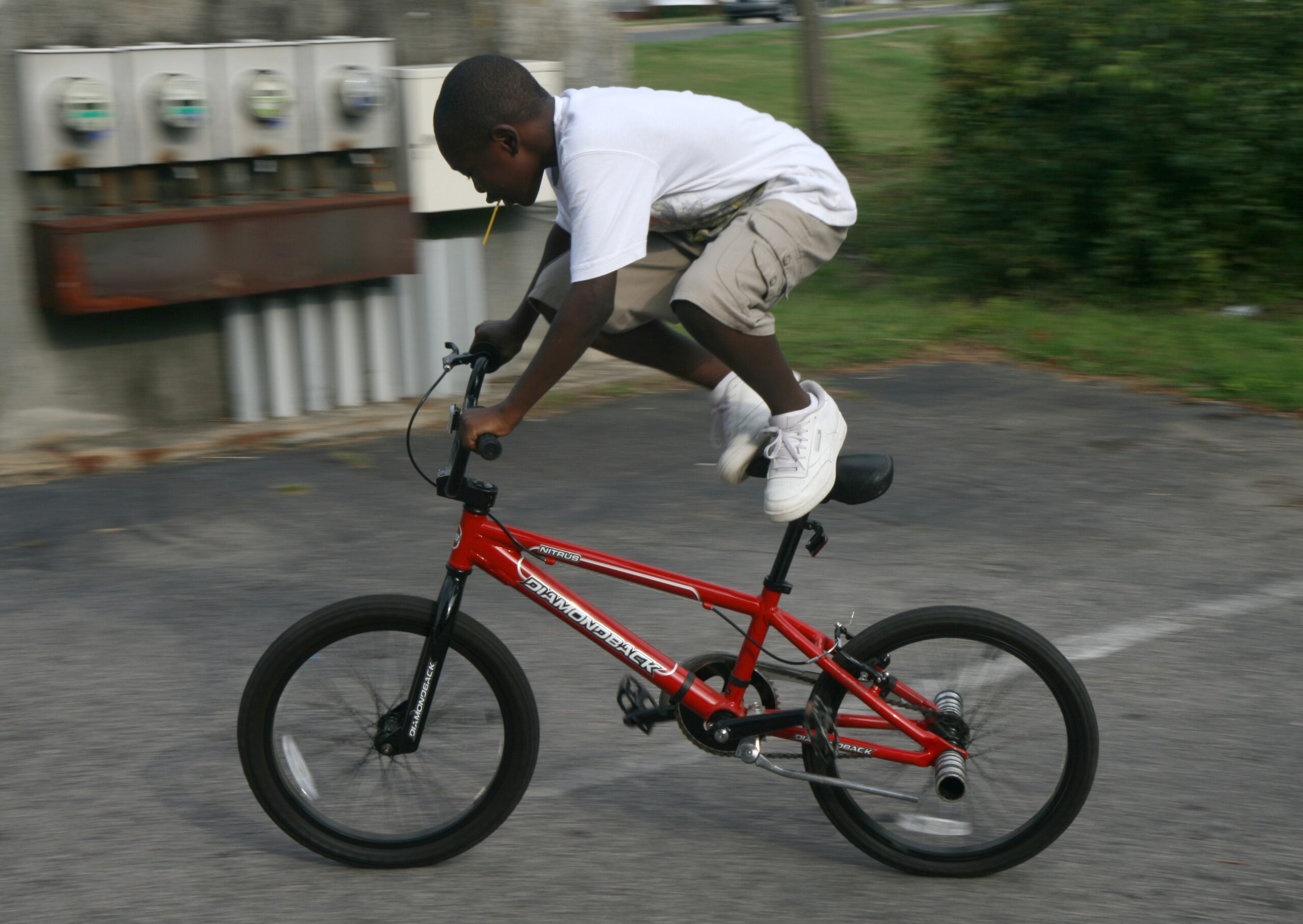 Kid riding BMX bicycle through suburban neighborhood like 80s kids