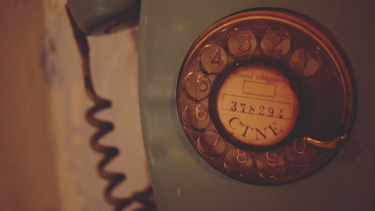 Macro closeup of rotary phone dial showing numbered holes for dialing