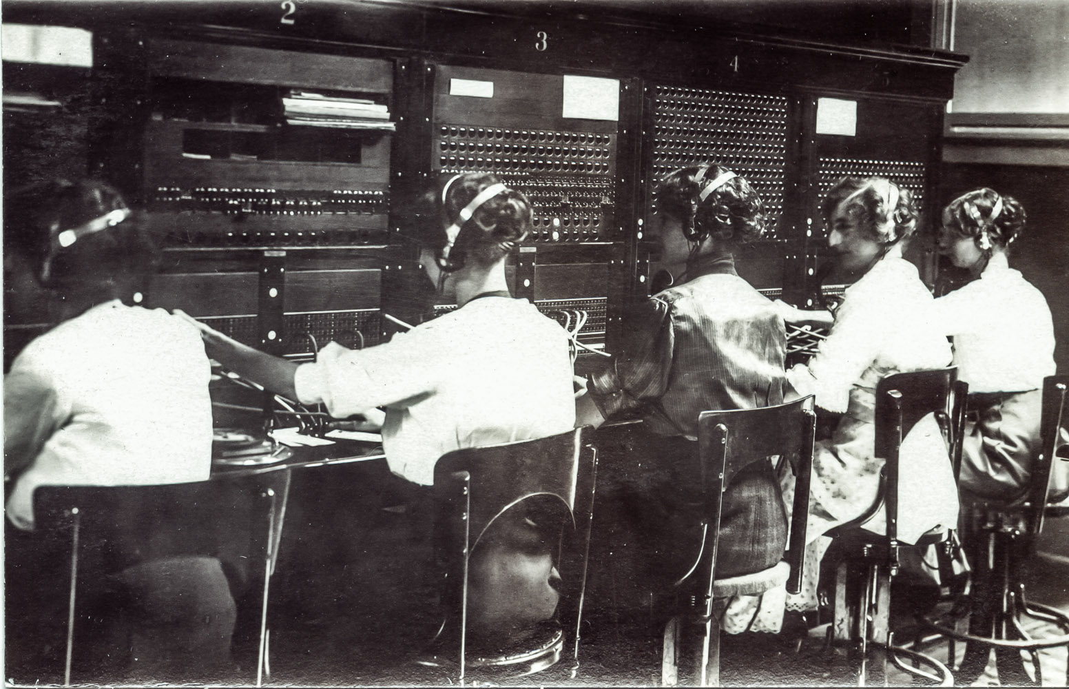 Row of vintage telephone operators at switchboard