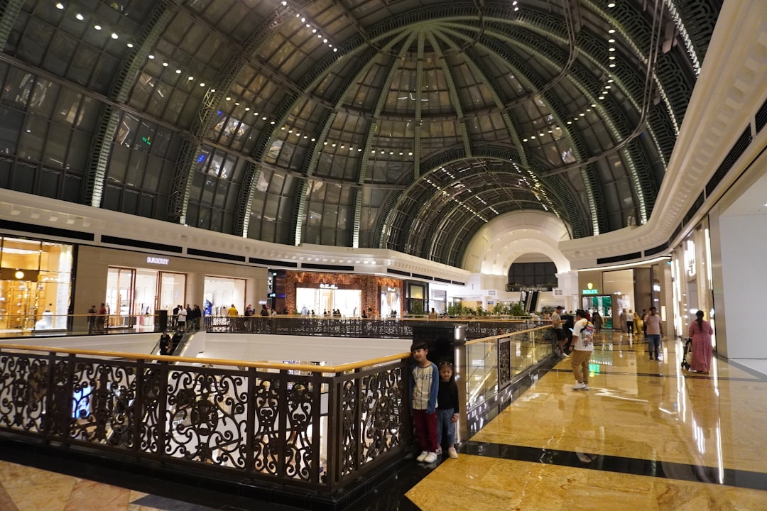 Grand shopping mall atrium with glass dome ceiling and multiple levels of stores