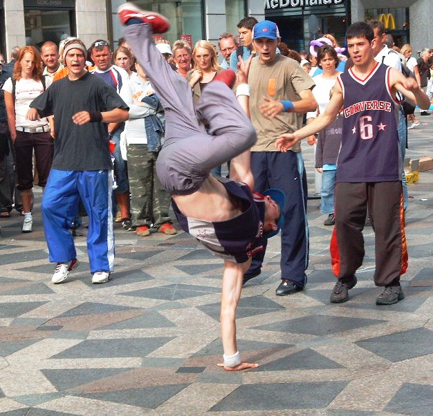 B-boy breakdancing on the street surrounded by a crowd — hip hop street culture