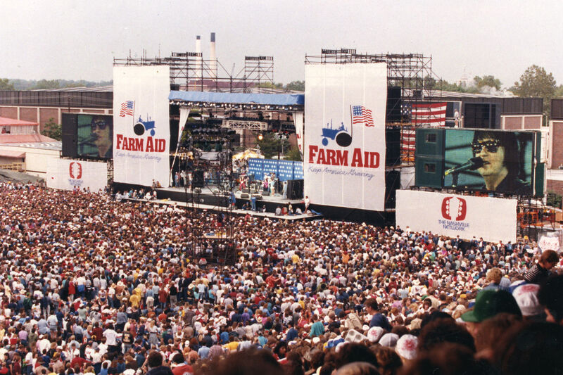 Farm Aid concert crowd with hands raised at the Hoosier Dome in 1990
