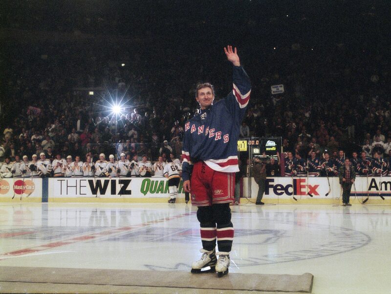 Wayne Gretzky waves goodbye at center ice as opposing players applaud during his final NHL game in 1999