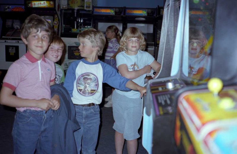 Kids playing 80s arcade games at a pizza parlor arcade in the early 1980s