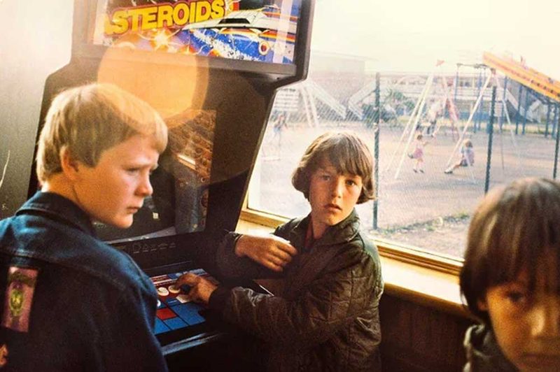 Boys playing the Asteroids arcade cabinet during the 80s coin-op boom