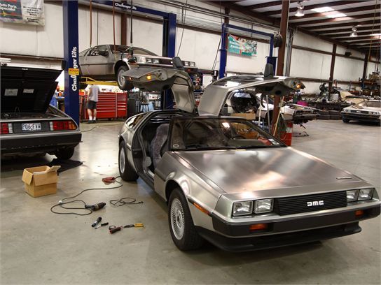DeLorean DMC-12 stainless steel sports car restoration shop two cars on lift