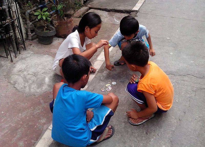 Kids playing pogs 90s schoolyard milk cap game on pavement