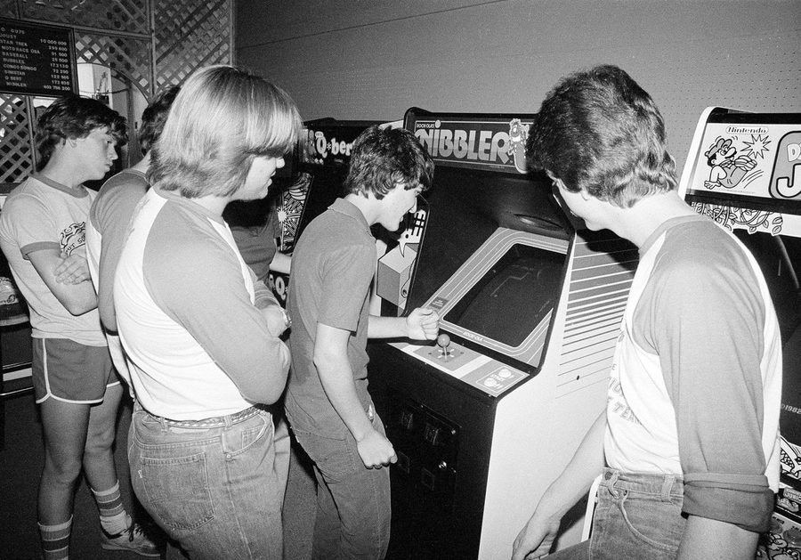 Teenagers crowded around a Nibbler arcade cabinet in Ottumwa Iowa 1983