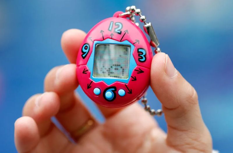 Original Tamagotchi in a hand showing the iconic egg-shaped device scale