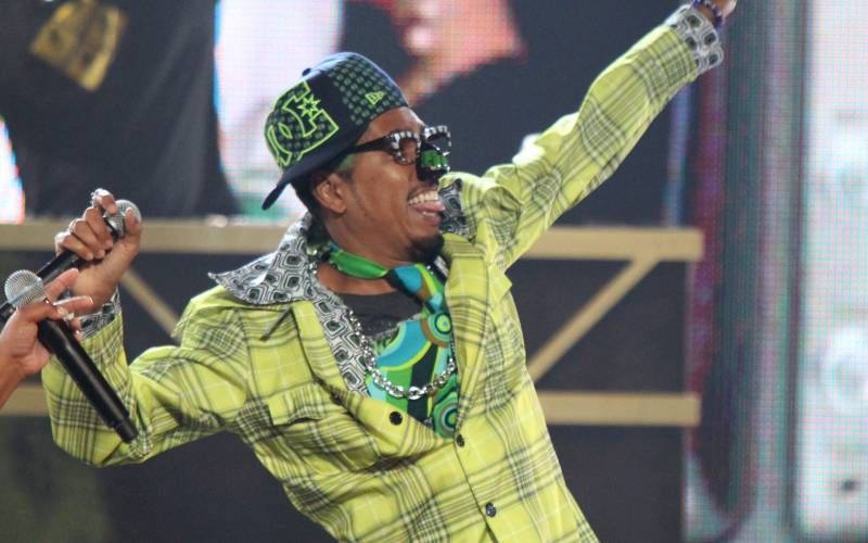 Shock G of Digital Underground performing on stage in plaid suit