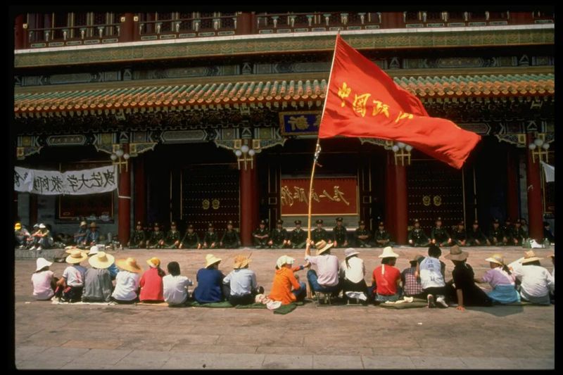 Students sit in front of soldiers with red Chinese flag 1989 Tiananmen protests