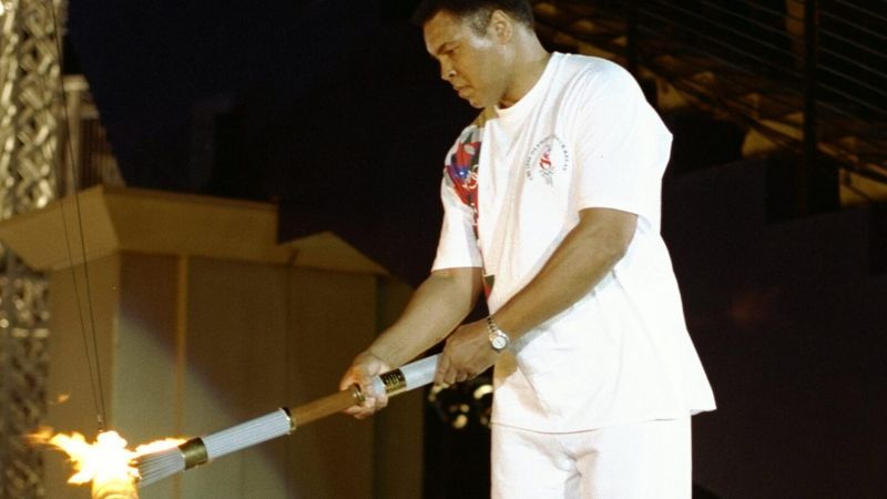 Muhammad Ali bends to light the Olympic flame at the 1996 Atlanta opening ceremony