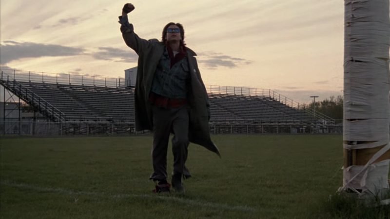 Judd Nelson as John Bender raising fist in iconic Breakfast Club closing shot on football field