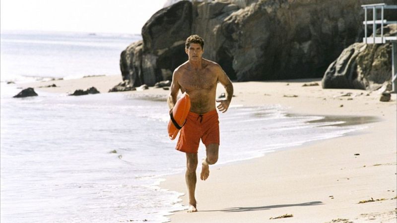 David Hasselhoff as Mitch Buchannon running on the beach with a rescue buoy