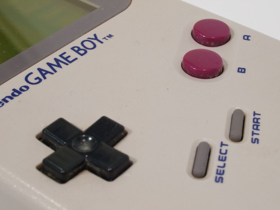 Close-up of the original Nintendo Game Boy controls showing the D-pad, magenta A and B buttons and green monochrome screen
