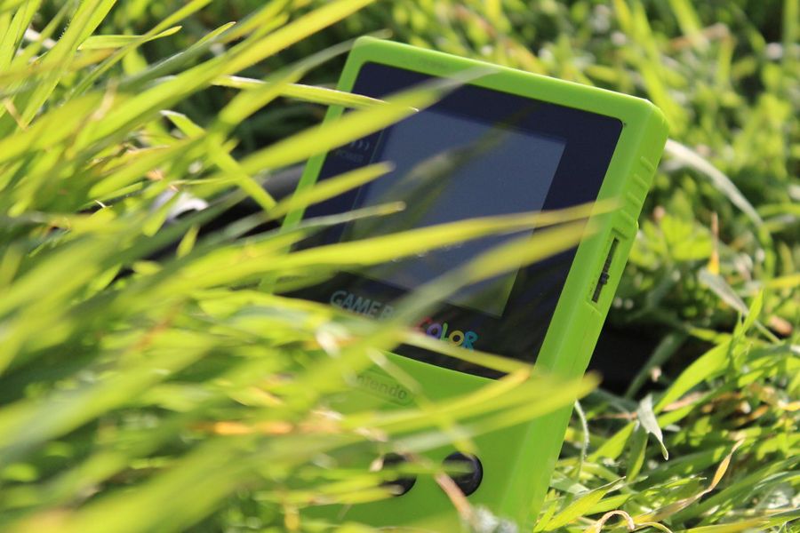Green Nintendo Game Boy Color handheld console resting outdoors in grass