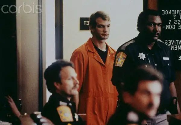 Jeffrey Dahmer in orange prison jumpsuit escorted by Milwaukee County Sheriff deputies to court, 1991