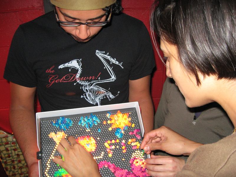 Two people making a picture on a vintage Lite-Brite toy