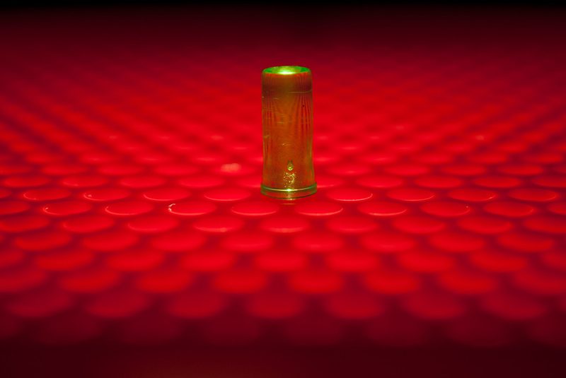 Close-up of a single translucent Lite-Brite peg conducting green light