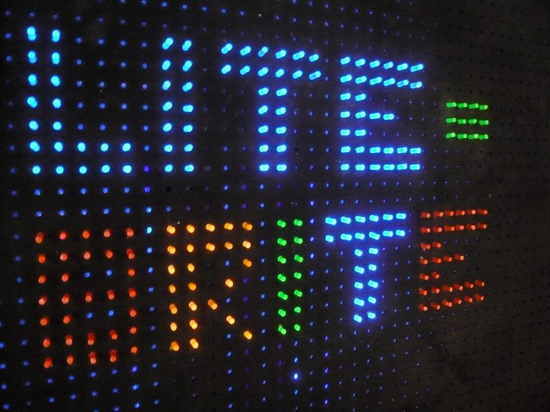 The words Lite-Brite spelled out in glowing colored pegs