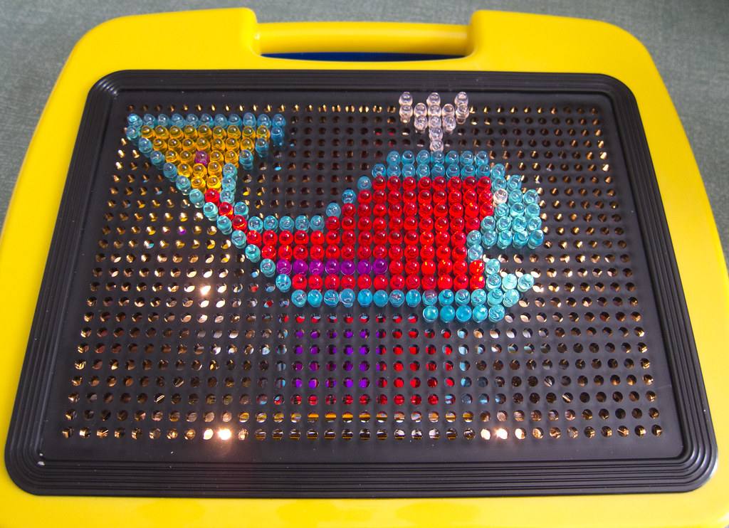 Lite-Brite toy lit up with a colorful design on the black screen