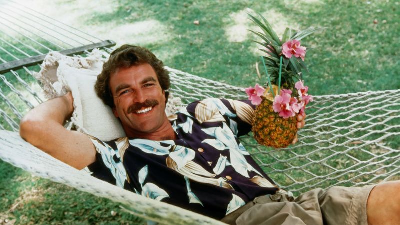 Magnum PI Tom Selleck relaxing in hammock with tropical pineapple drink Hawaii