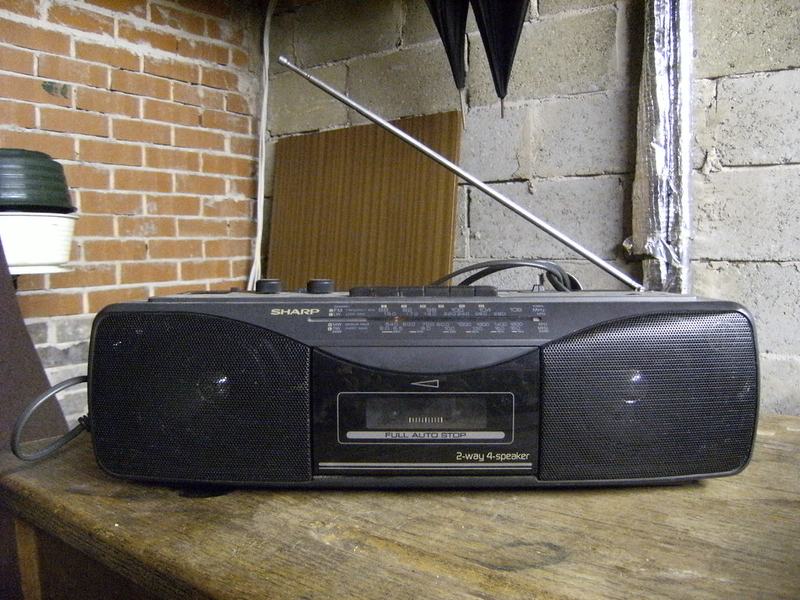 Black Sharp QT260 vintage boombox with dual cassette on a brick wall
