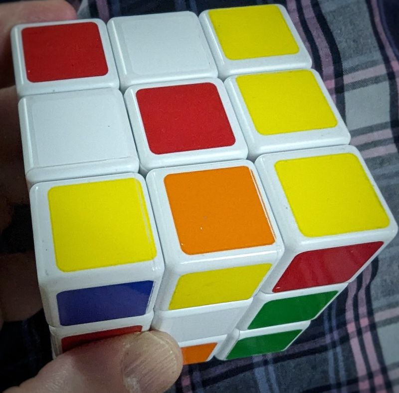 A colorful Rubik's Cube held up, partially scrambled