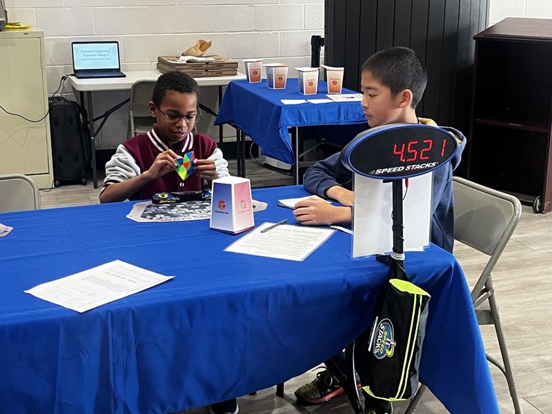 Kids at a speedcubing competition solving Rubik's Cubes against a timer