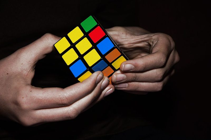 Hands holding a classic 3x3 Rubik's Cube in dramatic light