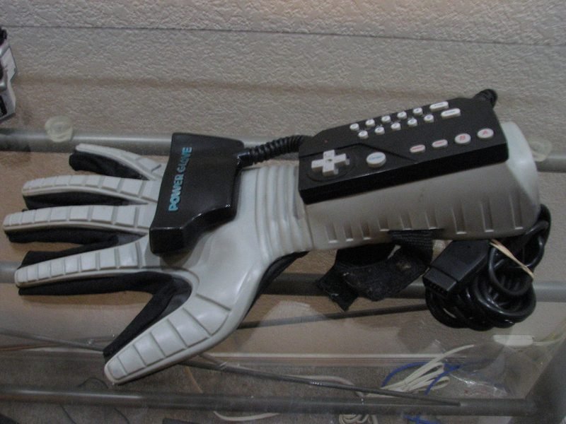 Vintage Nintendo Power Glove in a collector's display case alongside other NES accessories