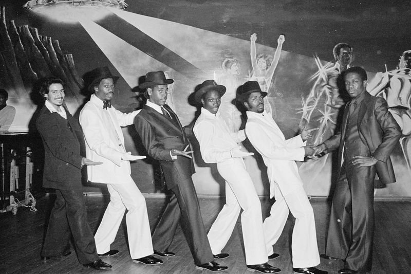 Group of men in white suits at a Bronx hip-hop club, early 1980s