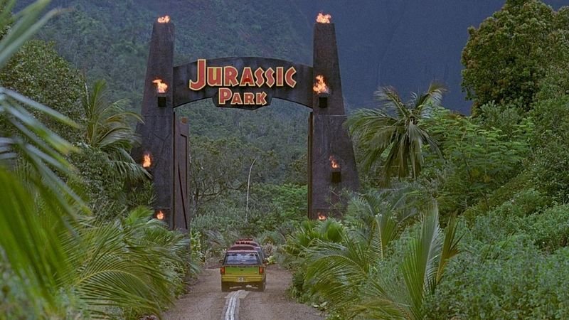 Jurassic Park original entrance arch with park sign and green Jeep approaching