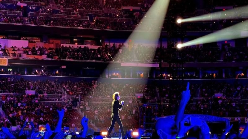 Mick Jagger performing under a stage spotlight at a Rolling Stones concert