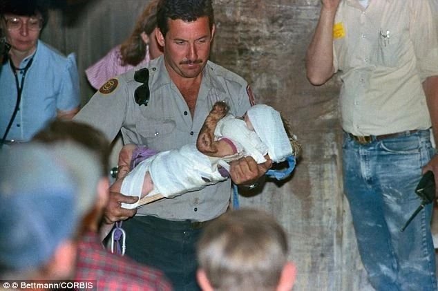 Paramedic carrying bandaged Jessica McClure through a crowd after the well rescue