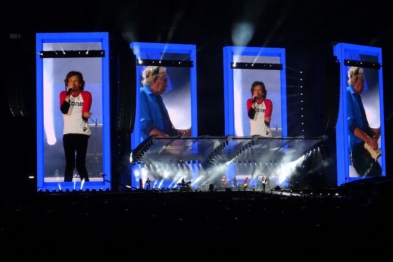 Mick Jagger spotlighted alone on a massive arena stage during a Rolling Stones concert