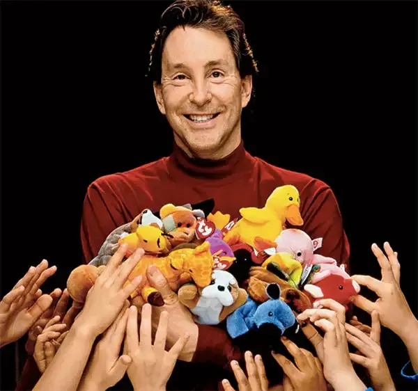 Ty Warner holding an armful of Beanie Babies as children's hands reach up for them